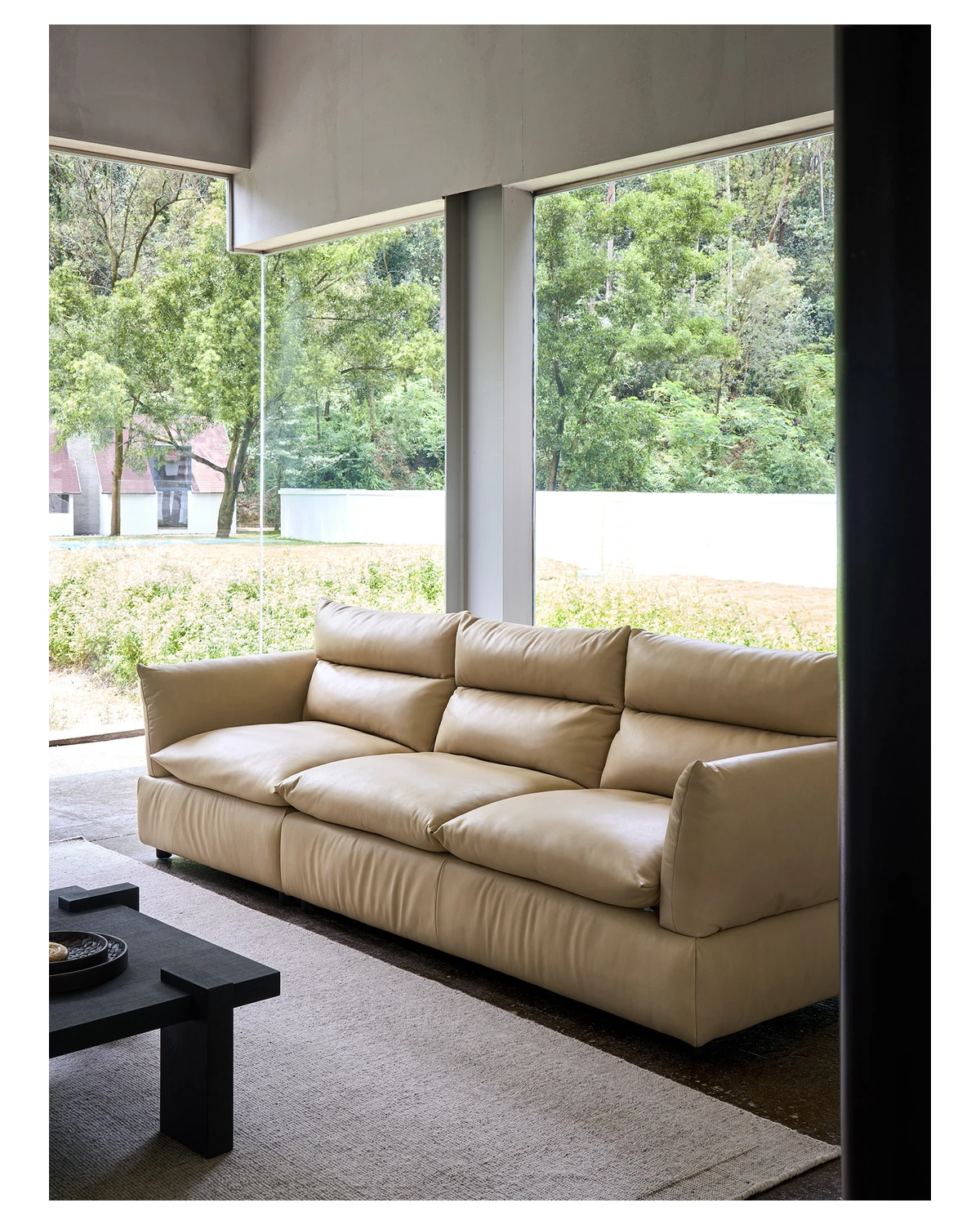 Tan full-grain leather sofa in a bright living room with a garden view