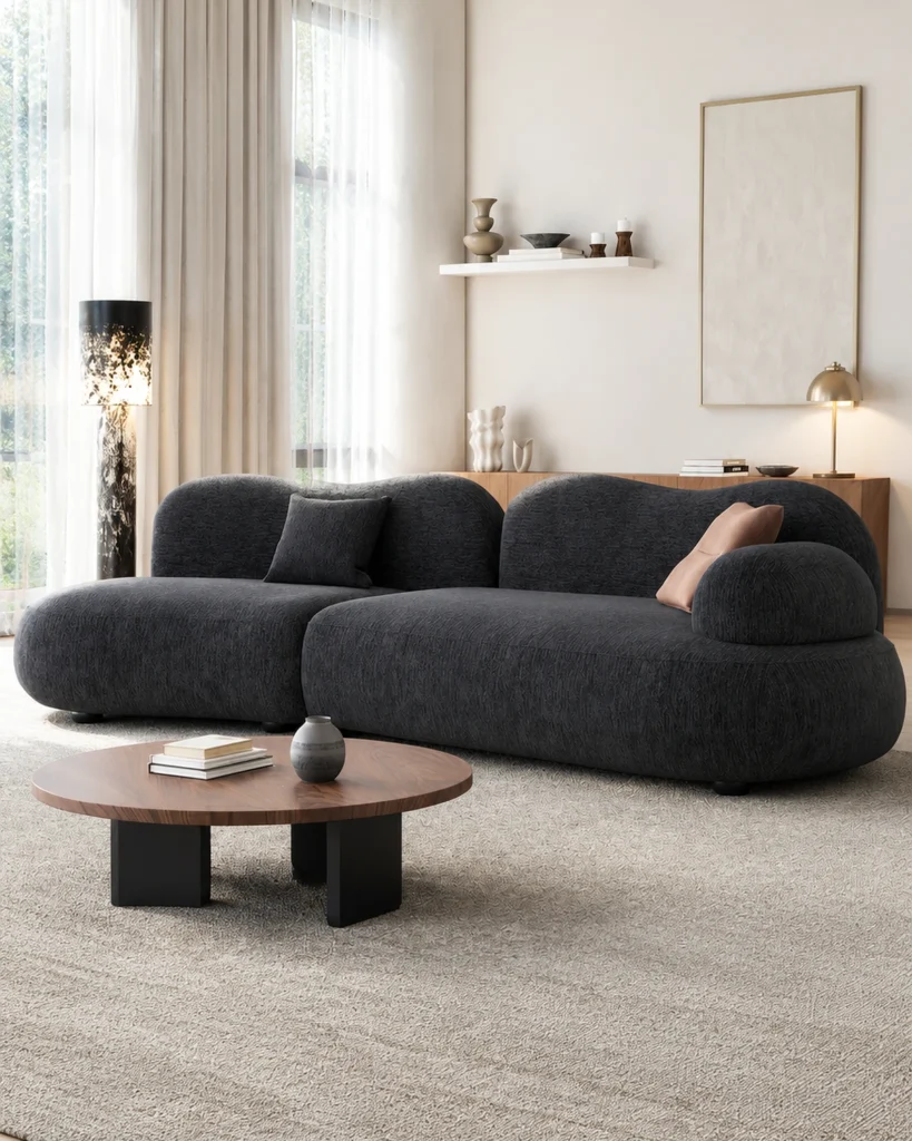 Ink grey cloud sofa in a warm minimal living room with a round wood coffee table